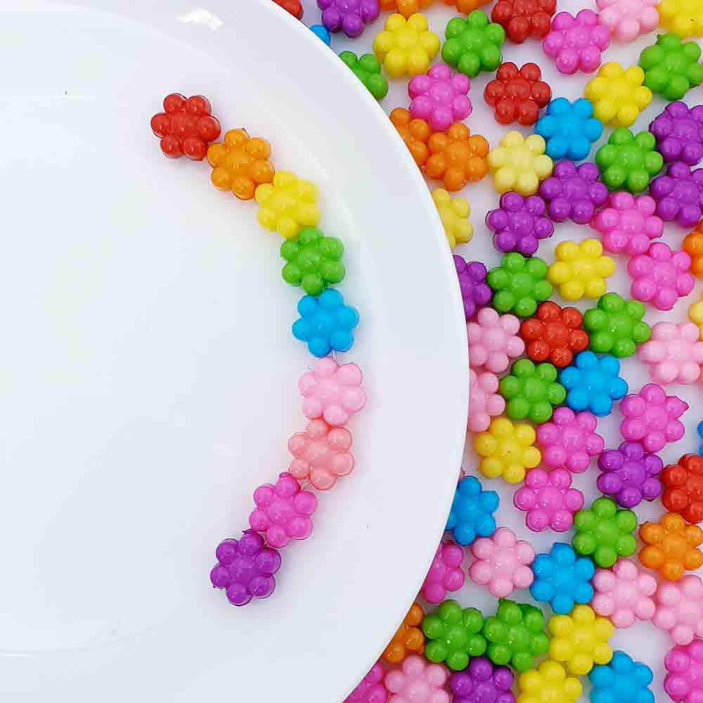 아크릴 컬러 꽃키링 플라워 비즈 키링을 하얀 접시위에 올려두었습니다 접시 아래에는 플라워 비즈키링의 여러가지색상이 놓여있습니다.