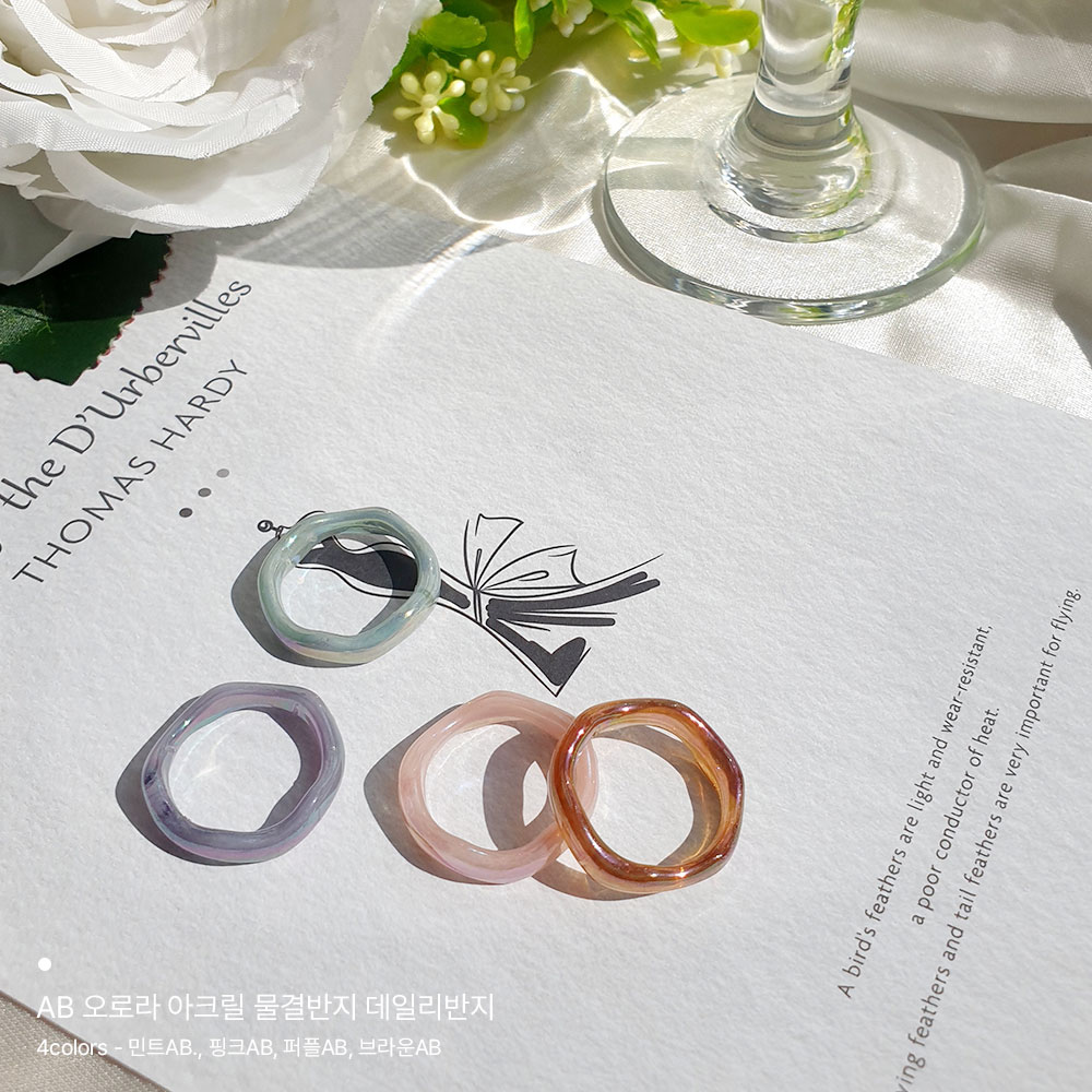 이 이미지는 회색종이위에 AB 오로라 아크릴 물결반지 4가지 컬러가 위에 자유롭게 놓여져있습니다. 주위에는 흰색장미가 보이고 와인잔 밑부분만 조금 보입니다.
AB 오로라 아크릴 물결반지의 특징은 잔잔한 바다 물결같은 패턴과 반짝이는 오로라 컬러입니다.